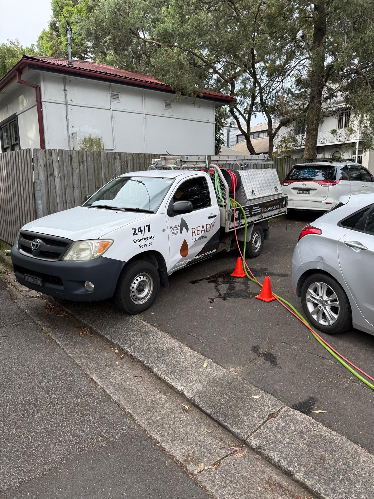 Ready Plumbing 24/7 emergency ute on site with drain jetter hoses run into a property