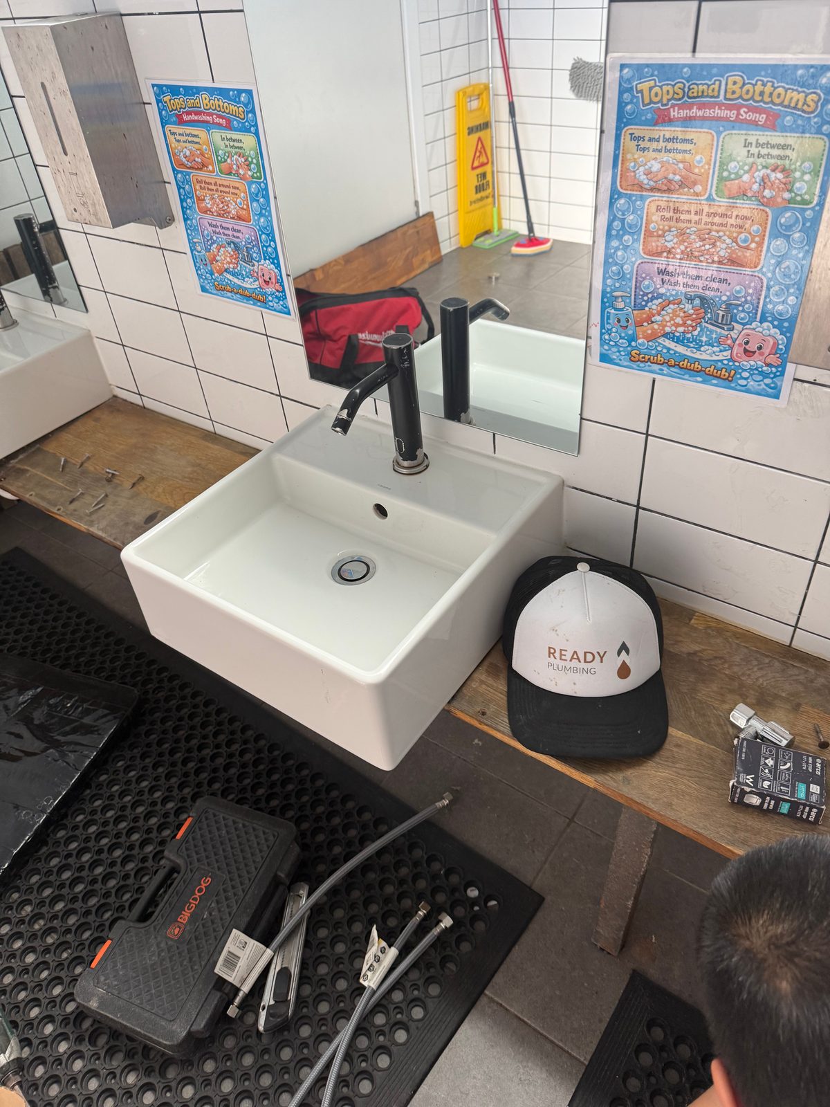New black lever tap installed on a child-height basin in Brookvale, below the childcare’s handwashing poster