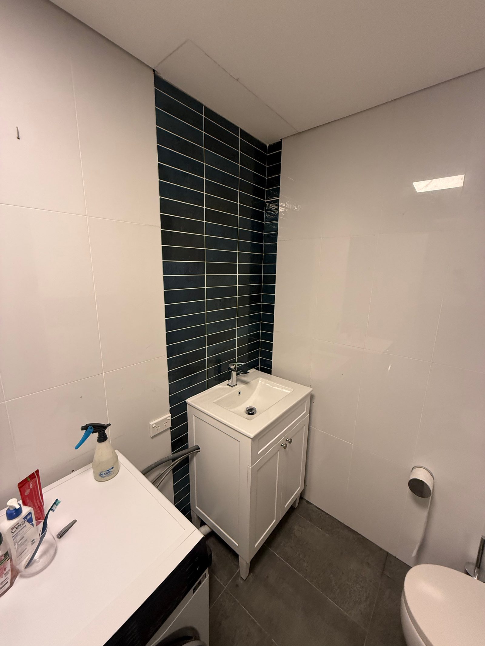 The new, right-sized vanity fitted against the re-tiled wall, with the shower screen opened up behind it
